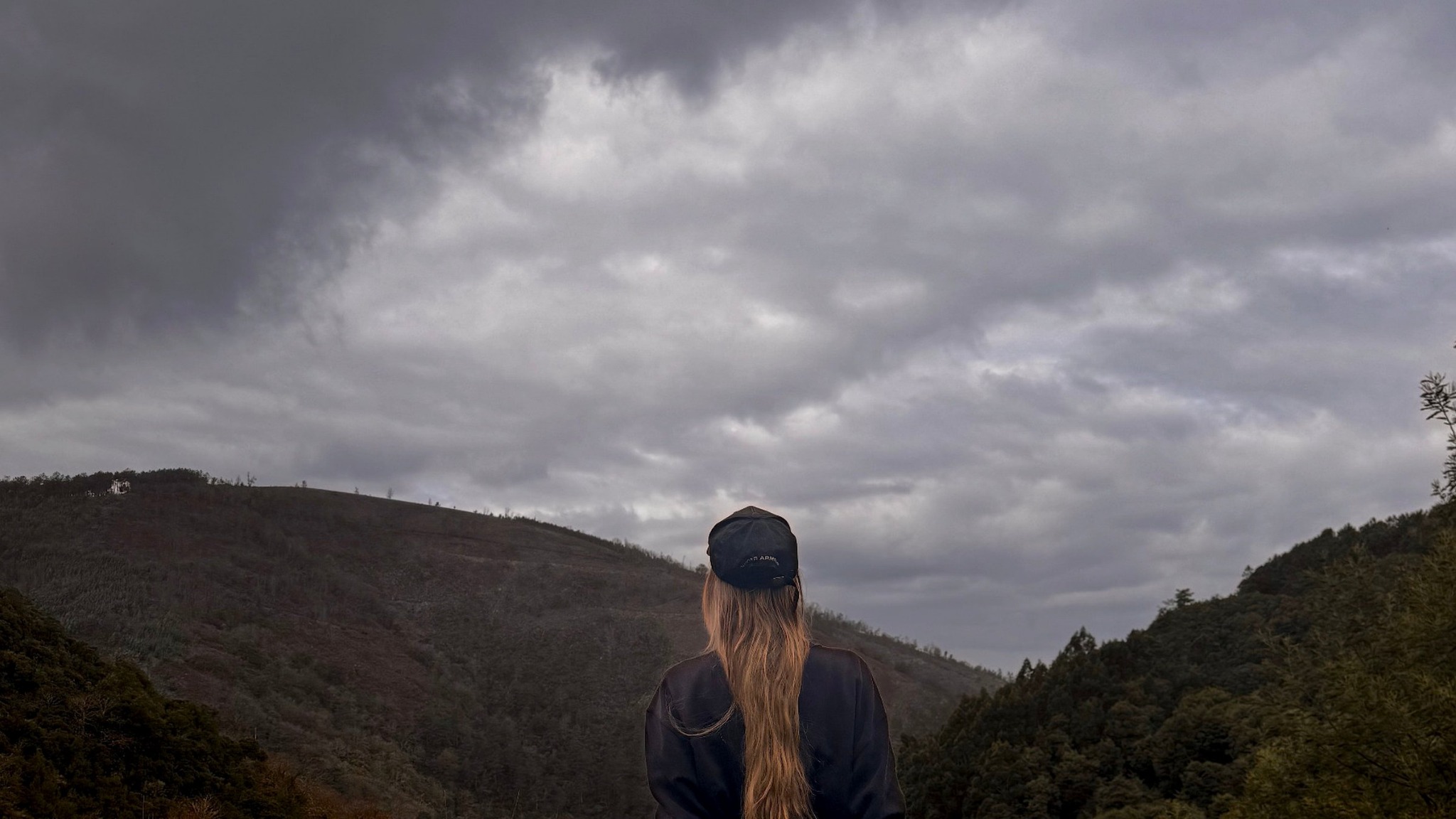 Isabel Saldanha de costas, diante de uma paisagem montanhosa