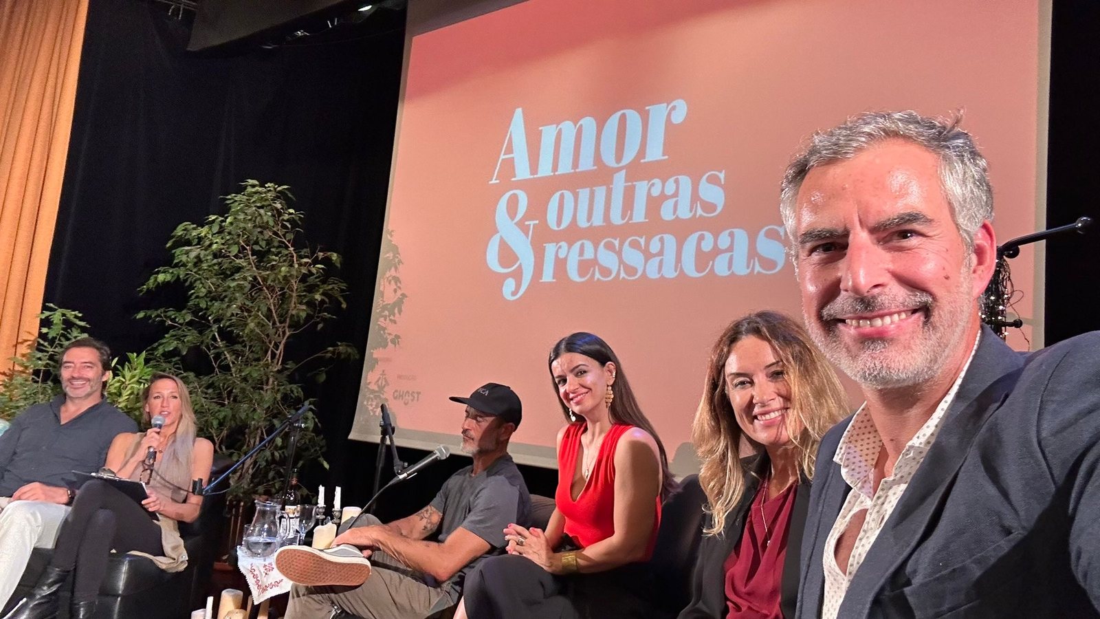 Painel de conversa em palco, com o t&iacute;tulo Amor & Outras Ressacas projetado atr&aacute;s