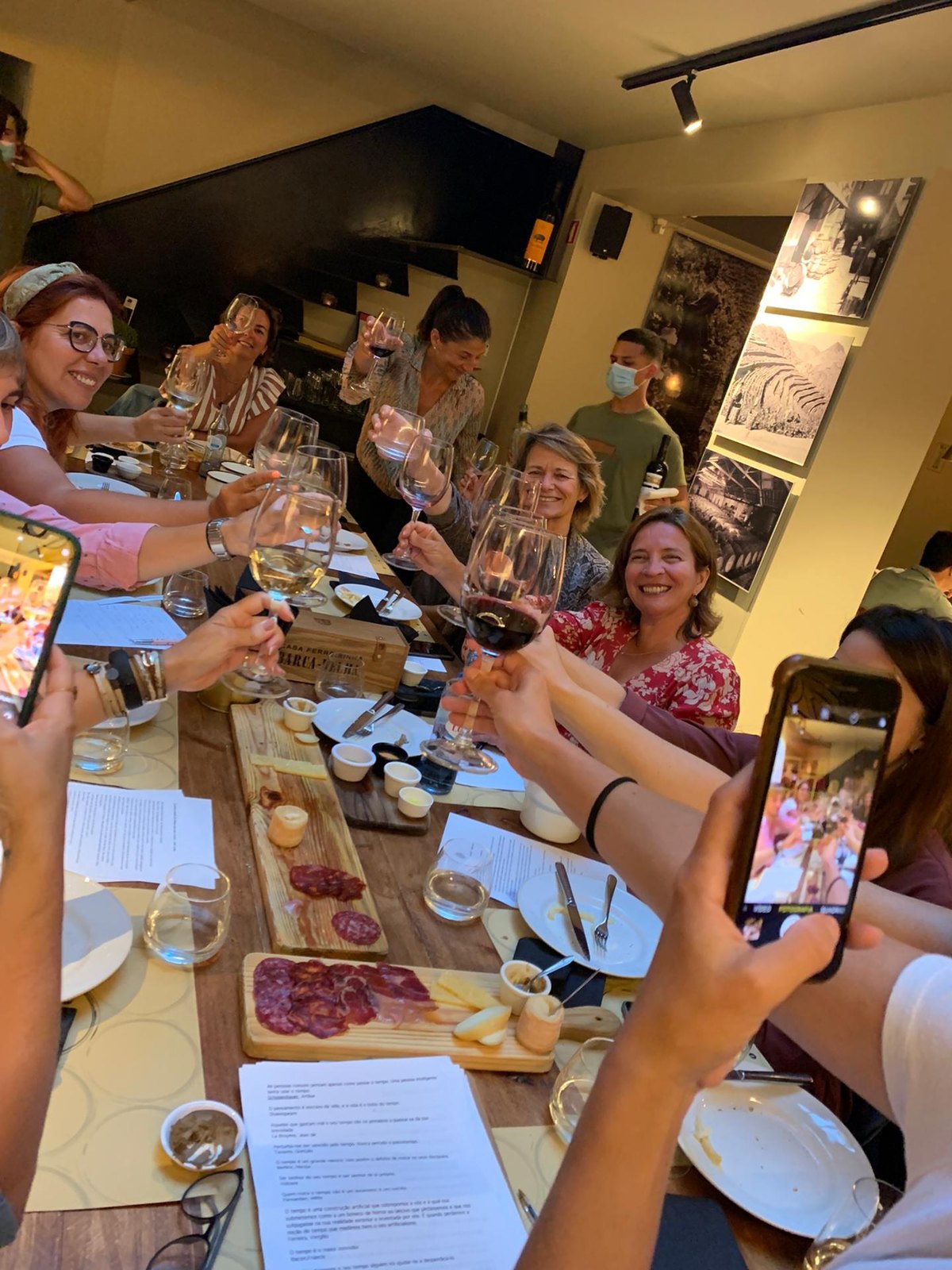 Grupo &agrave; volta de uma mesa comprida, a brindar com vinho